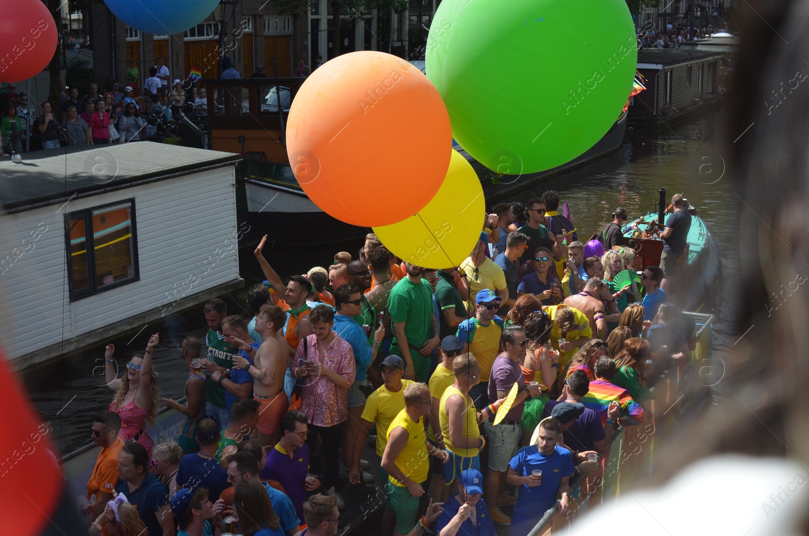 Photo of AMSTERDAM, NETHERLANDS - AUGUST 06, 2022: Many people in boat at LGBT pride parade on river