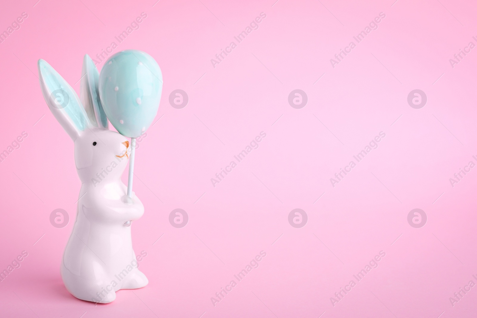 Photo of Easter bunny figure on pink background. Space for text