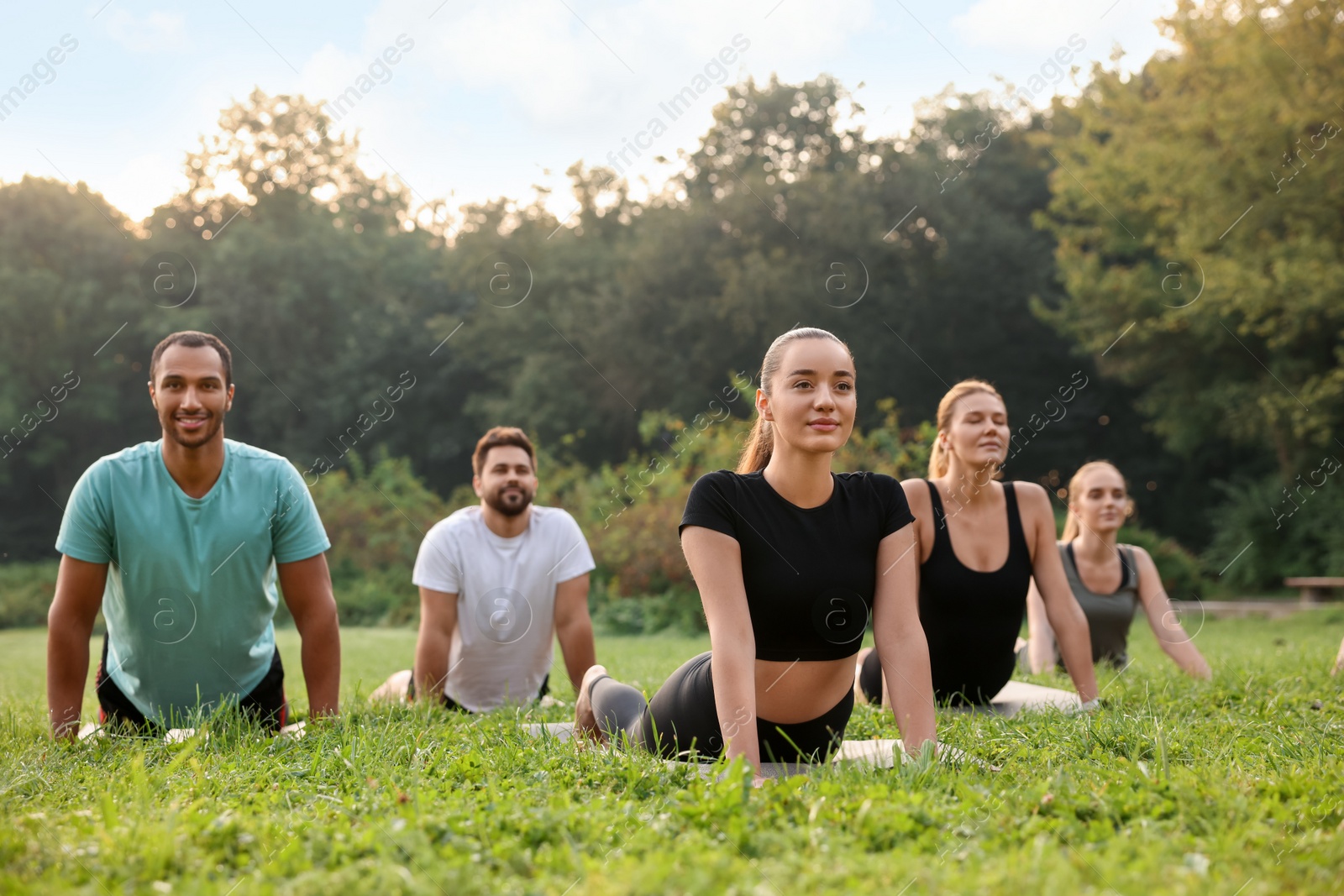 Photo of Group of people practicing yoga on mats outdoors