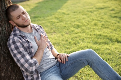 Man having heart attack on green grass in park