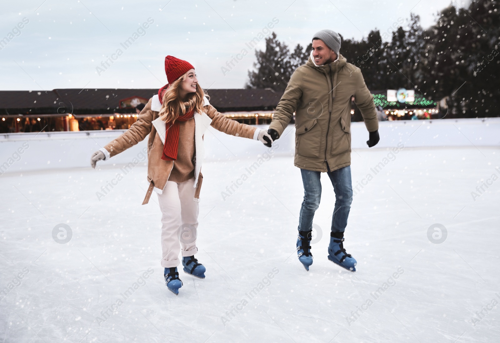 Image of Happy couple skating at outdoor ice rink