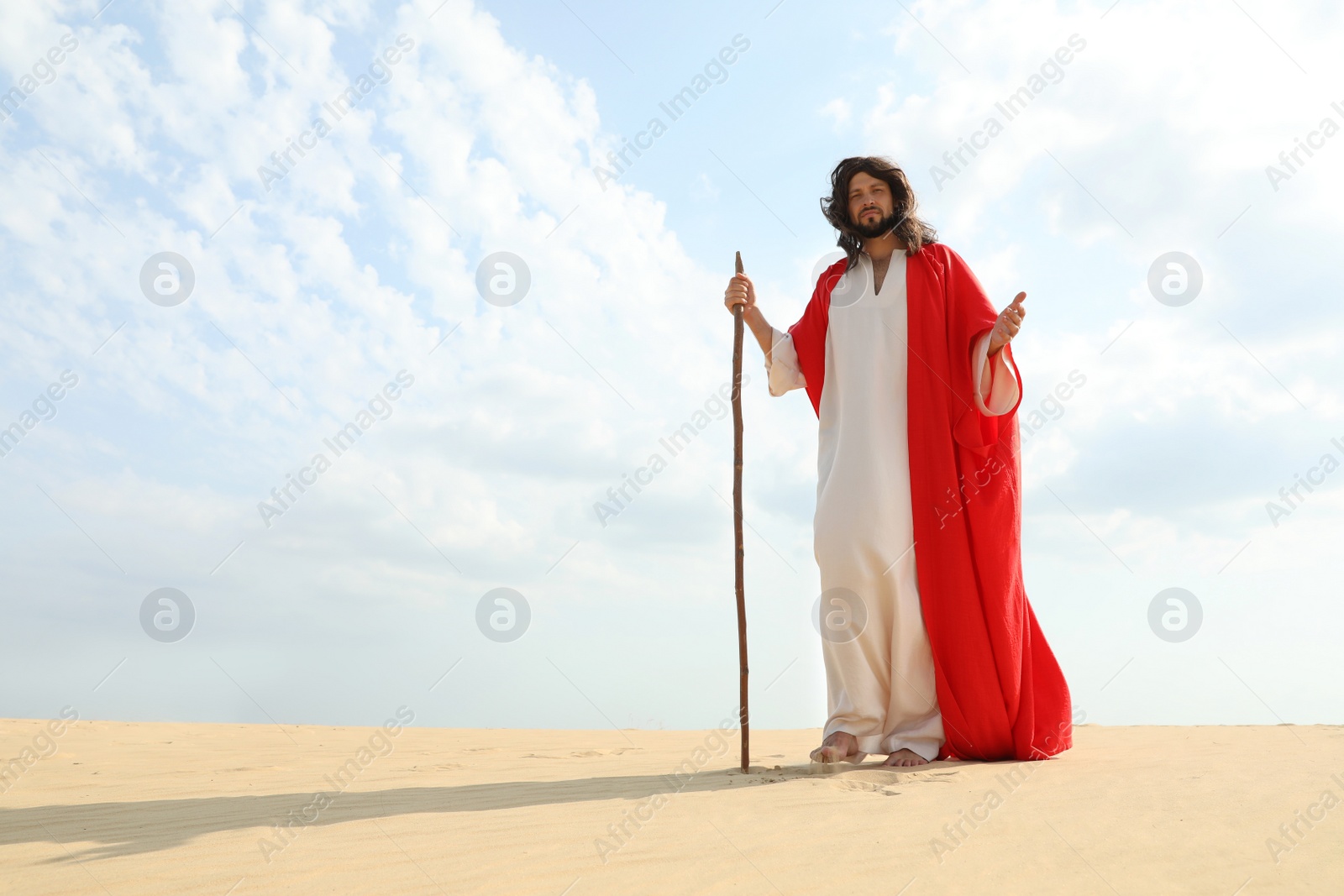 Photo of Jesus Christ walking with stick in desert. Space for text