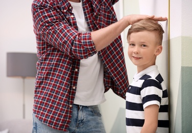 Young man measuring his son's height at home