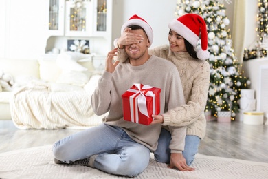 Young woman presenting Christmas gift to her boyfriend at home