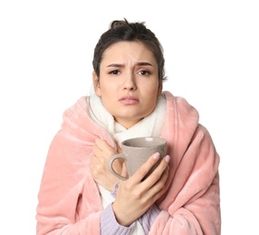 Young woman with cup of hot tea suffering from cold on white background