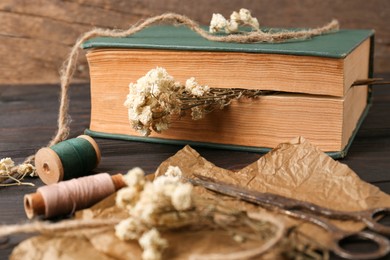 Book with flowers as bookmark on wooden table, closeup