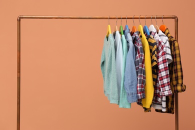 Rack with stylish children clothes on beige background