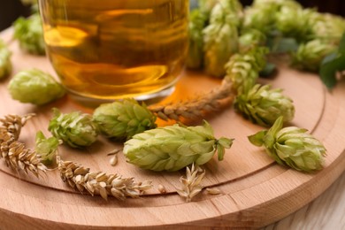 Beer, fresh hops and ears of wheat on wooden table, closeup