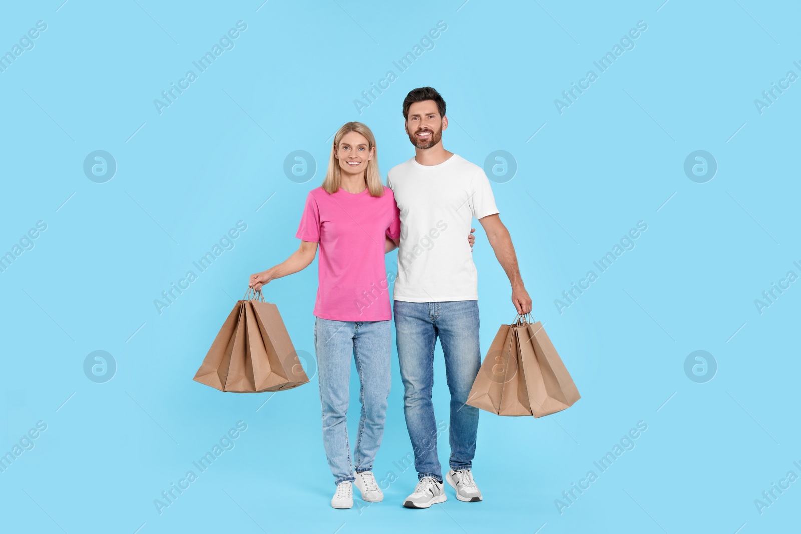 Photo of Family shopping. Happy couple with many paper bags on light blue background