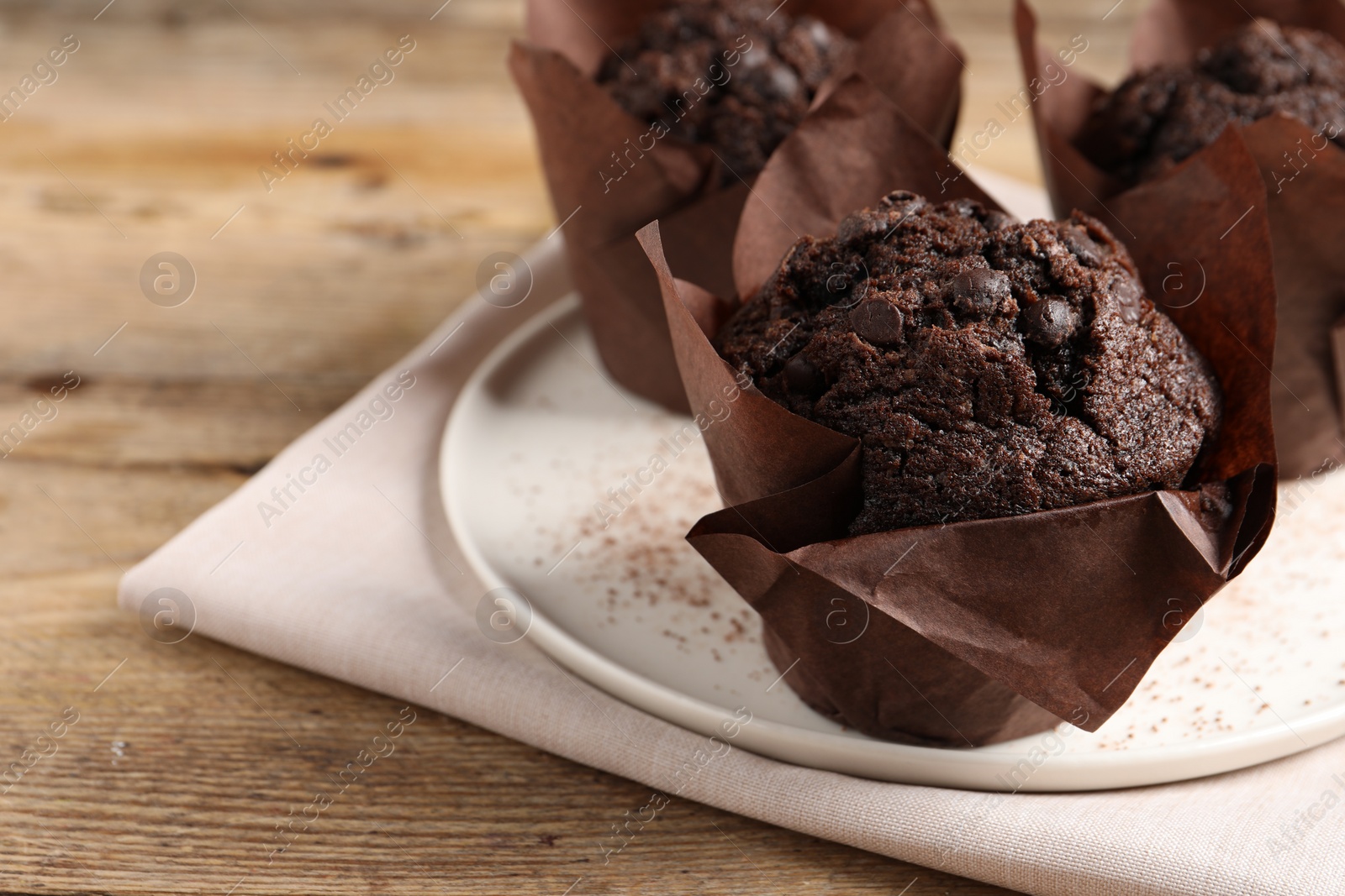 Photo of Tasty chocolate muffins on wooden table, closeup. Space for text