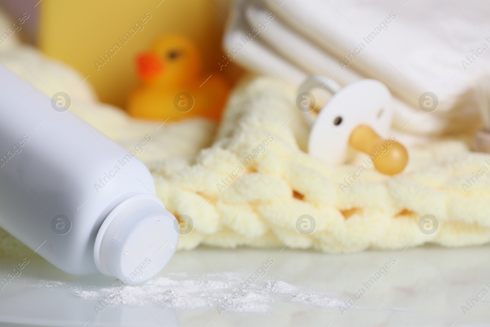 Photo of Overturned bottle of dusting powder and accessories on white table, space for text. Baby cosmetic product