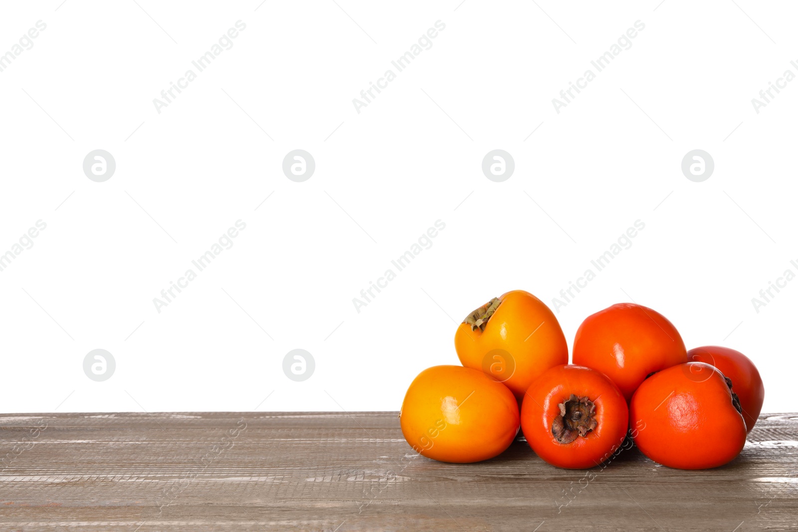 Photo of Delicious ripe juicy persimmons on wooden table against white background