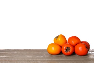 Delicious ripe juicy persimmons on wooden table against white background