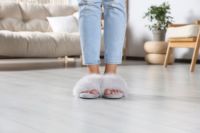 Photo of Woman wearing soft slippers at home, closeup of legs