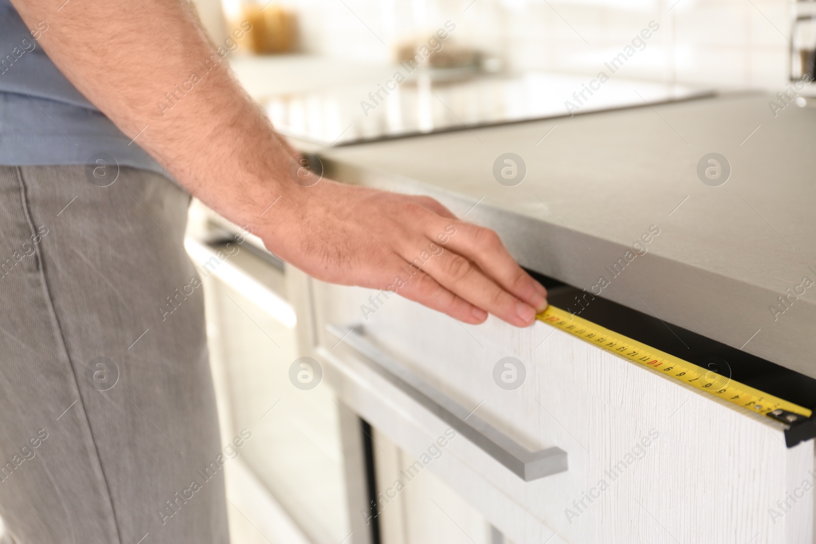 Photo of Man measuring kitchen furniture indoors, closeup. Construction tool