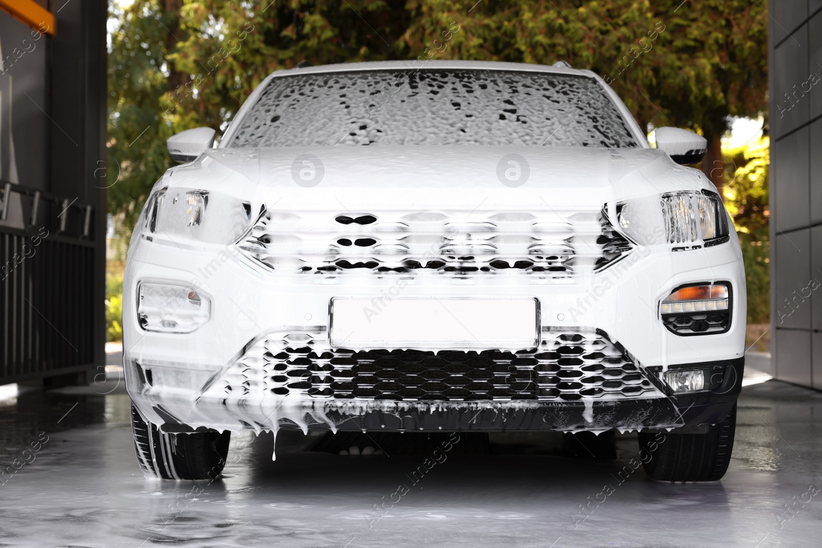 Photo of Auto covered with cleaning foam at outdoor car wash