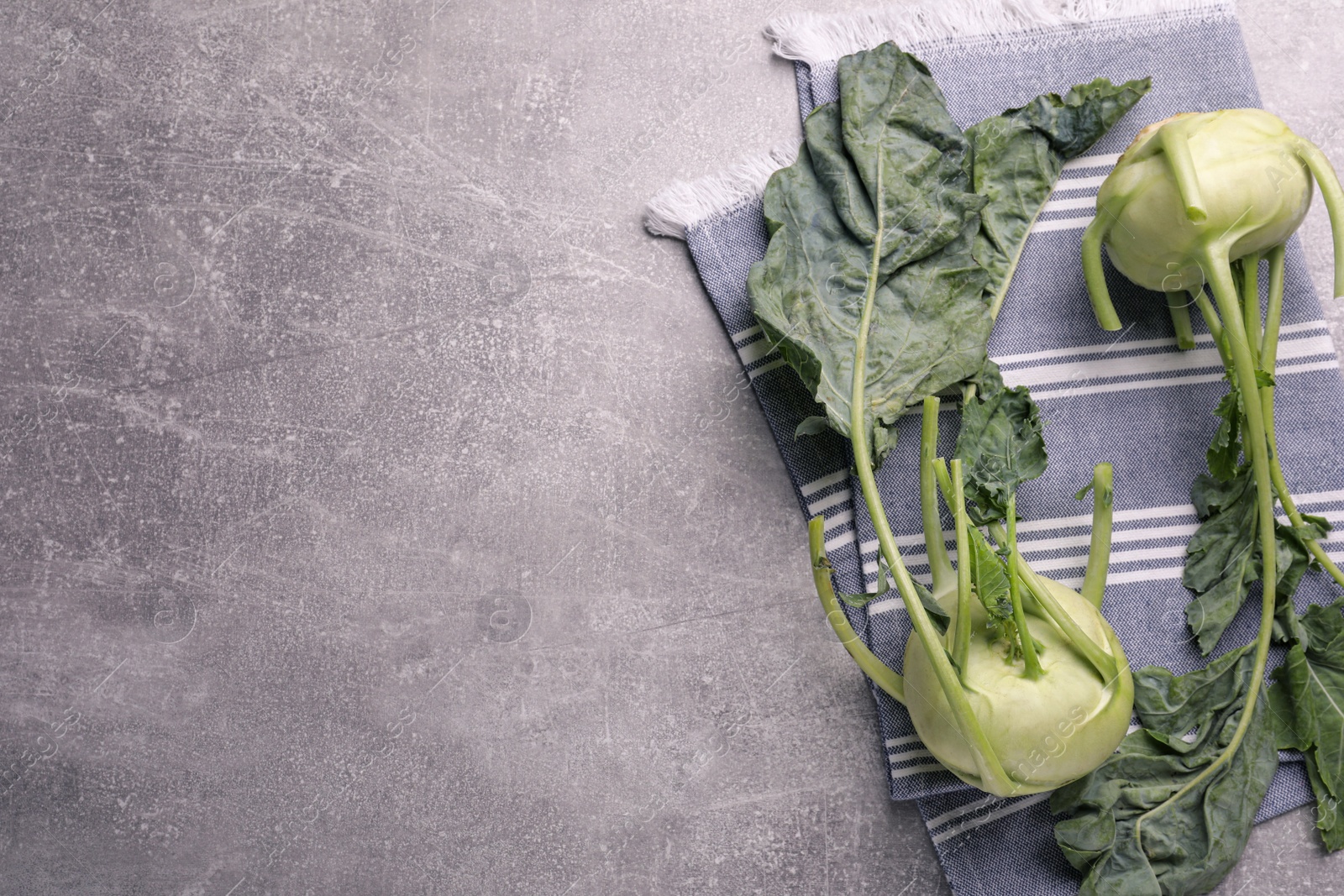 Photo of Whole ripe kohlrabi plants on grey table, flat lay. Space for text