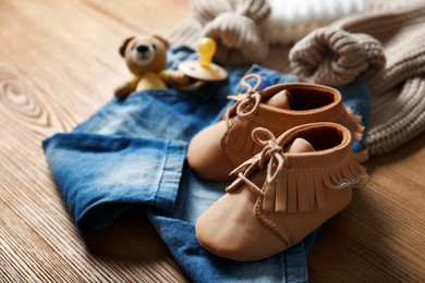 Photo of Children's shoes, clothes, toy and pacifier on wooden table