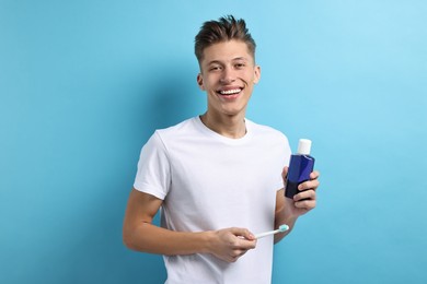 Photo of Young man with mouthwash and toothbrush on light blue background