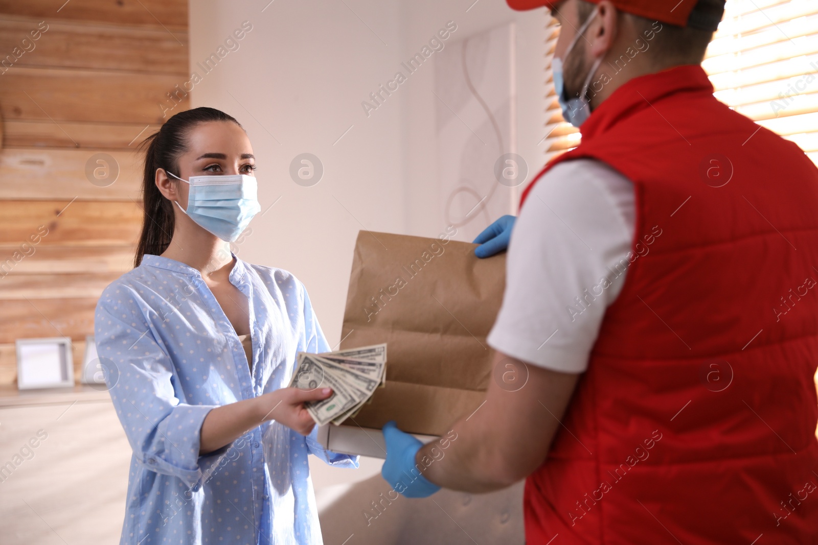 Photo of Young woman giving tips to deliveryman indoors