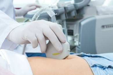 Doctor conducting ultrasound examination of internal organs in clinic, closeup