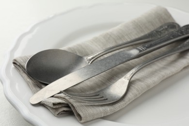 Photo of Stylish setting with cutlery, napkin and plate on table, closeup