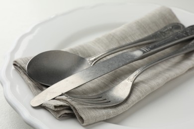 Stylish setting with cutlery, napkin and plate on table, closeup