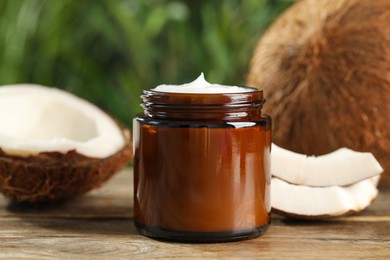 Photo of Jar of hand cream and coconut on wooden table