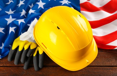 Photo of Yellow hard hat, gloves and American flag on wooden table