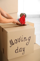 Photo of Woman packing carton box indoors, closeup. Moving day
