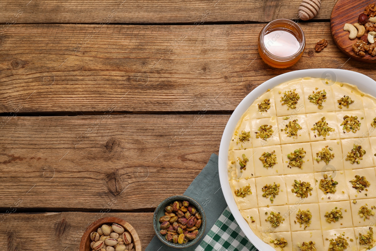 Photo of Making delicious baklava. Raw dough with ingredients on wooden table, flat lay and space for text