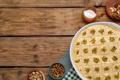 Photo of Making delicious baklava. Raw dough with ingredients on wooden table, flat lay and space for text