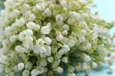 Beautiful lily of the valley bouquet on light blue background, closeup