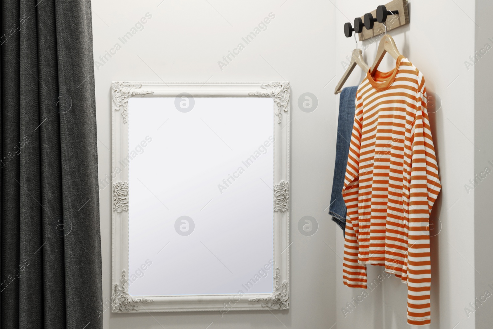 Photo of Dressing room with mirror in fashion store. Stylish design