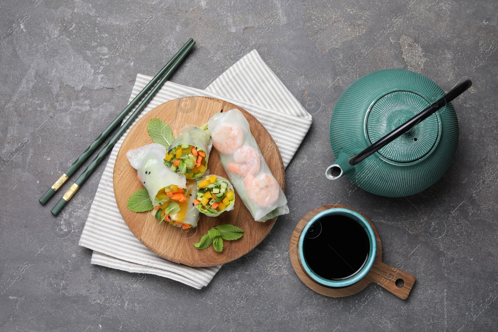 Photo of Tasty spring rolls served on grey textured table, flat lay