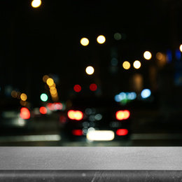 Empty grey marble surface and blurred view of night city. Bokeh effect 