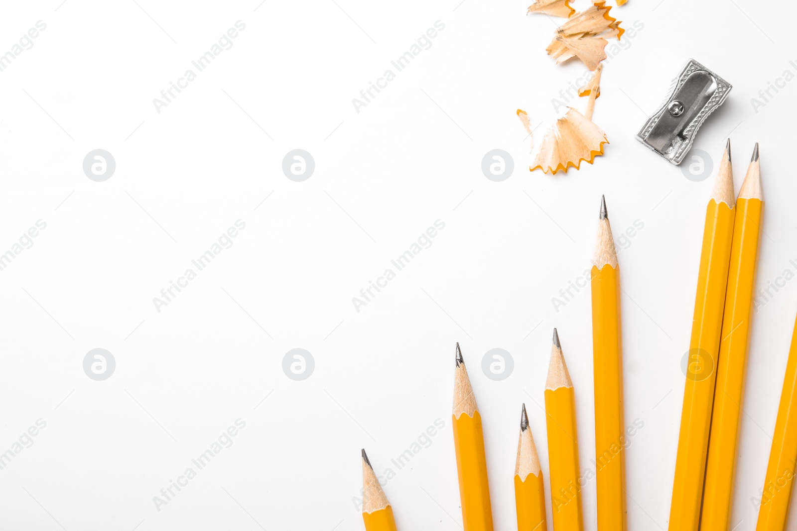 Photo of Graphite pencils, shavings and sharpener on white background, top view. Space for text