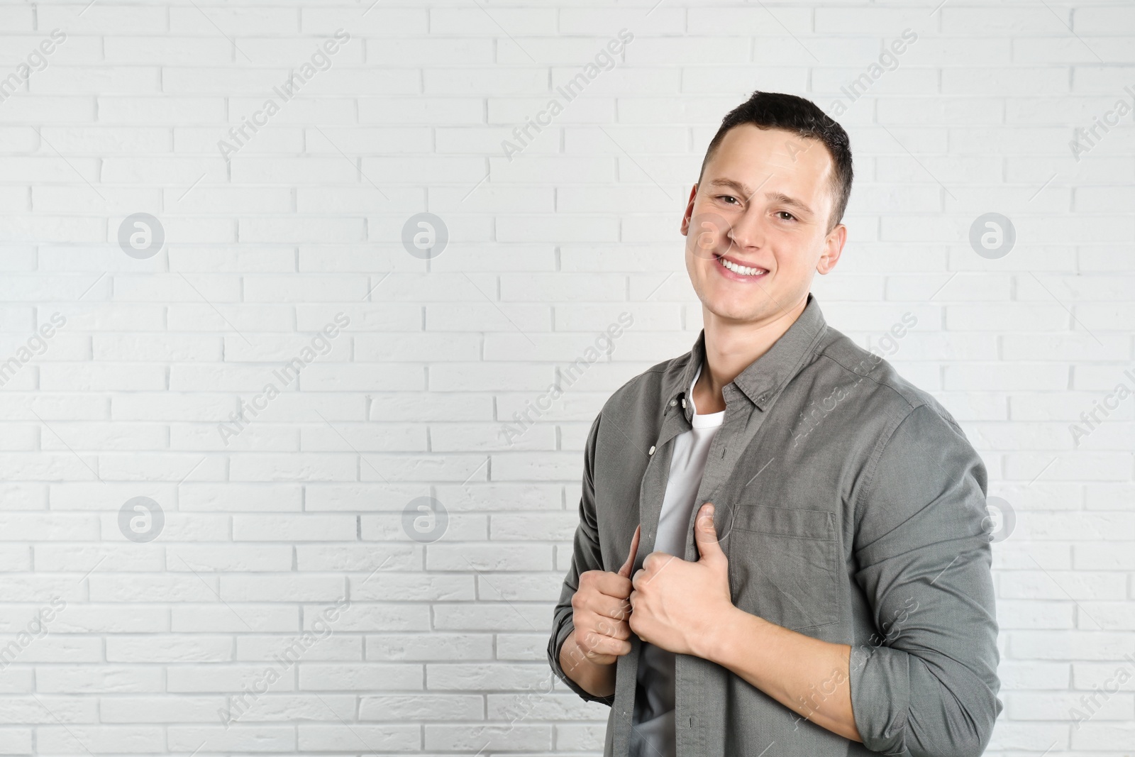 Photo of Handsome young man near white brick wall. Space for text