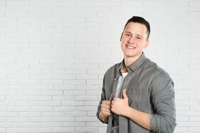 Handsome young man near white brick wall. Space for text