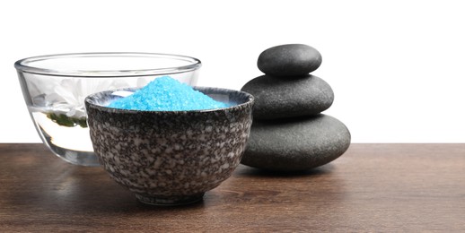 Light blue sea salt in bowl, spa stones and flowers on wooden table against white background