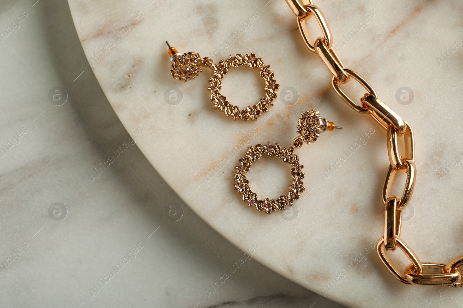 Photo of Stylish golden bijouterie on white marble table, top view