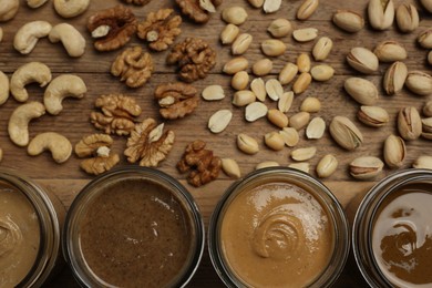 Photo of Nut butters in bowls and ingredients on wooden table, flat lay