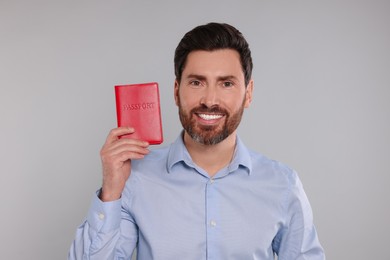 Immigration. Happy man with passport on gray background
