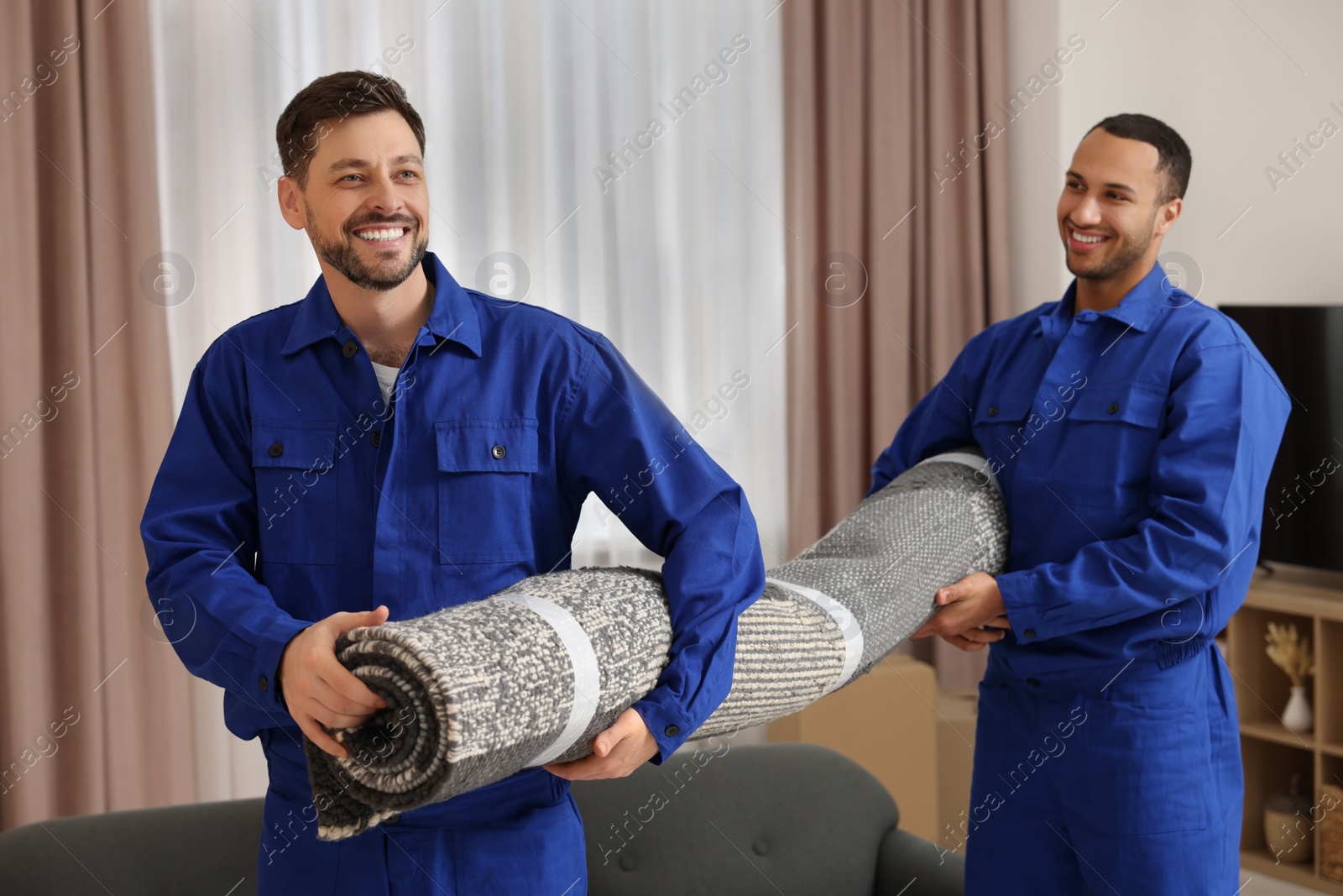 Photo of Male movers carrying carpet in new house