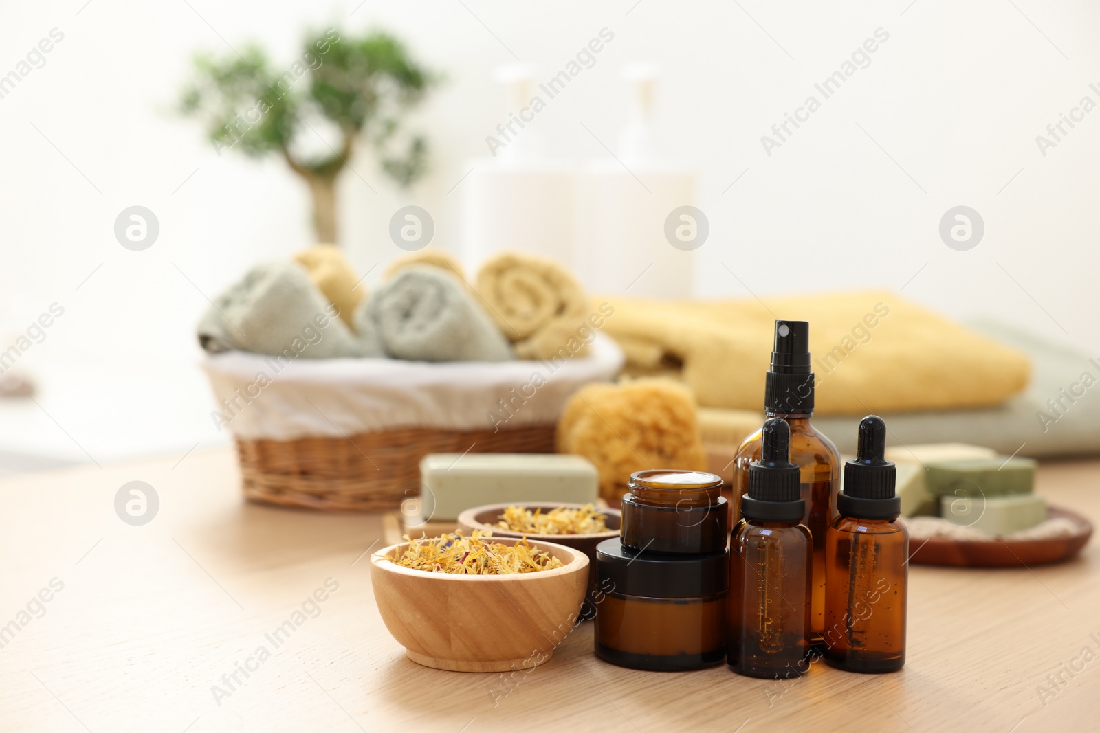 Photo of Bottles of essential oils, dry flowers and jars with cream on light wooden table. Spa therapy