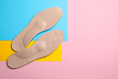 Photo of Pair of beige orthopedic breathable insoles on color background, flat lay. Space for text