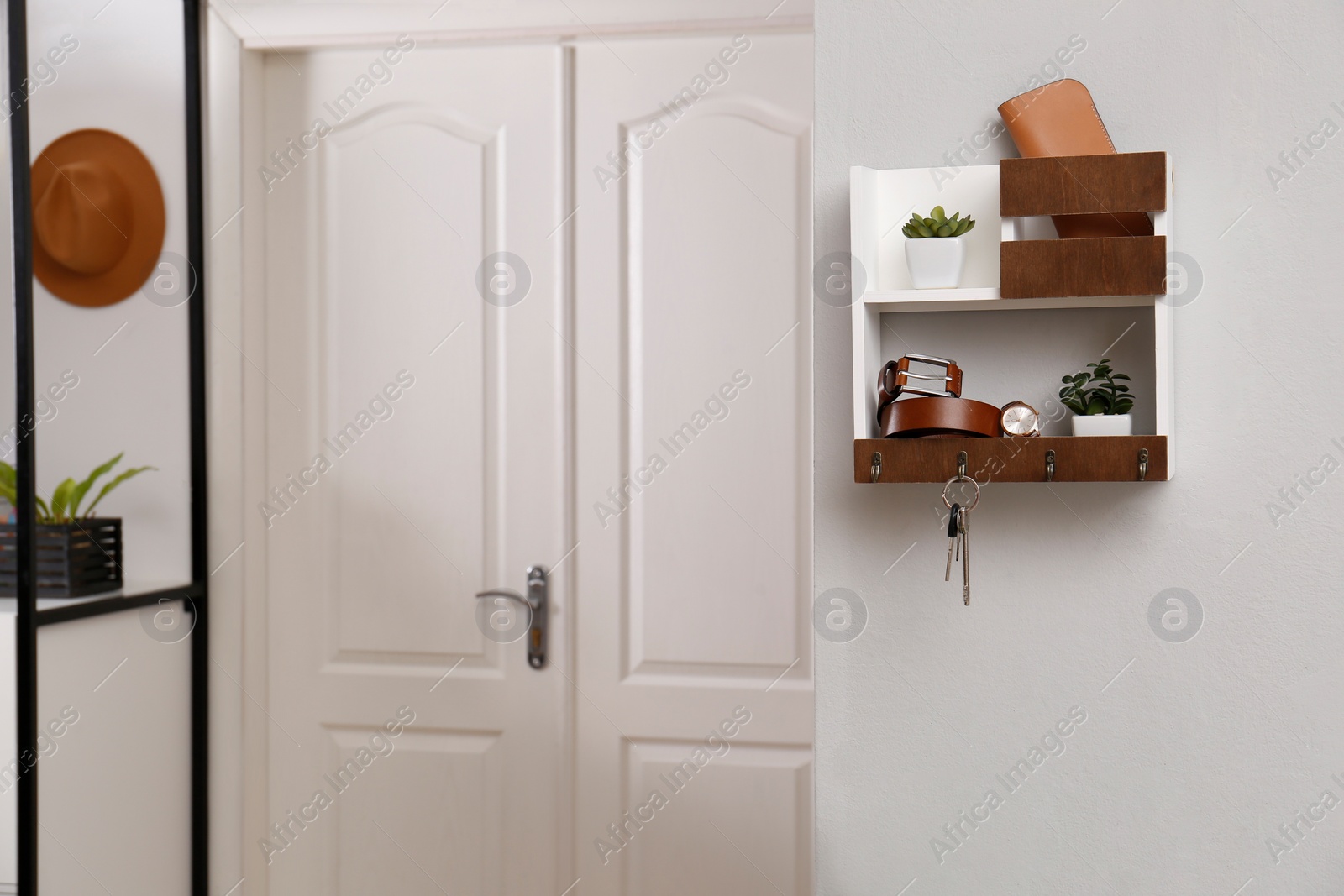 Photo of Hallway interior with stylish accessories and wooden hanger for keys on white wall