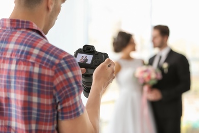 Photo of Professional photographer taking photo of wedding couple in studio