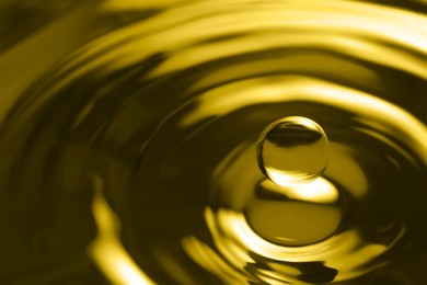 Image of Splash of golden oily liquid with drop as background, closeup