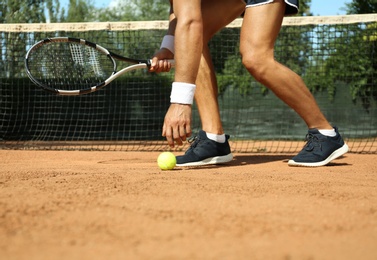 Photo of Sportsman playing tennis at court on sunny day, closeup